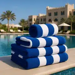 Striped pool towels stacked beside a hotel pool