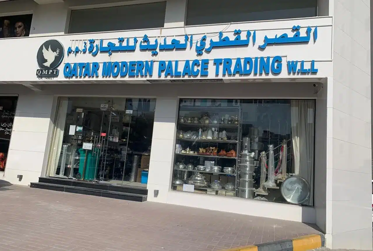 The QMPC shopfront on Hiteen Street in Doha, signed Qatar Modern Palace Trading W.L.L. in English and Arabic, with stock visible through the glass.